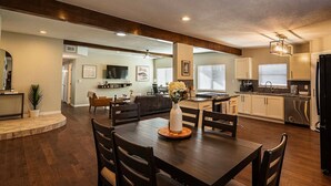A spacious living area with a dining table, chairs, and a kitchen in the background. - Family Home w/ Outdoor Playground, Patio, King Bed (El Paso)