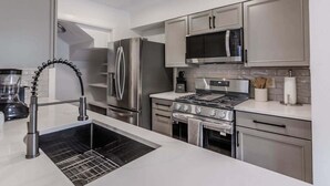 Uma cozinha moderna com eletrodomésticos de aço inoxidável, forno embutido e micro-ondas.