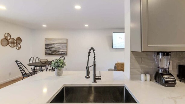 Uma cozinha moderna com uma ilha central, uma pia embutida e um liquidificador no balcão.