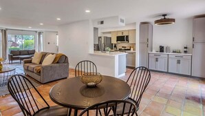 Uma cozinha moderna com armários cinza, uma ilha central e um espaço de refeições com uma mesa redonda e cadeiras.