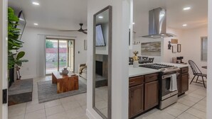 A modern kitchen with a central island, a dining area with a sofa, and a large mirror. - Family home w/outdoor playground (El Paso)