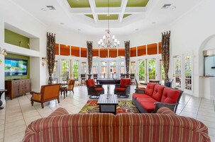 A spacious living area with a large sofa, red chairs, a coffee table, and a television.