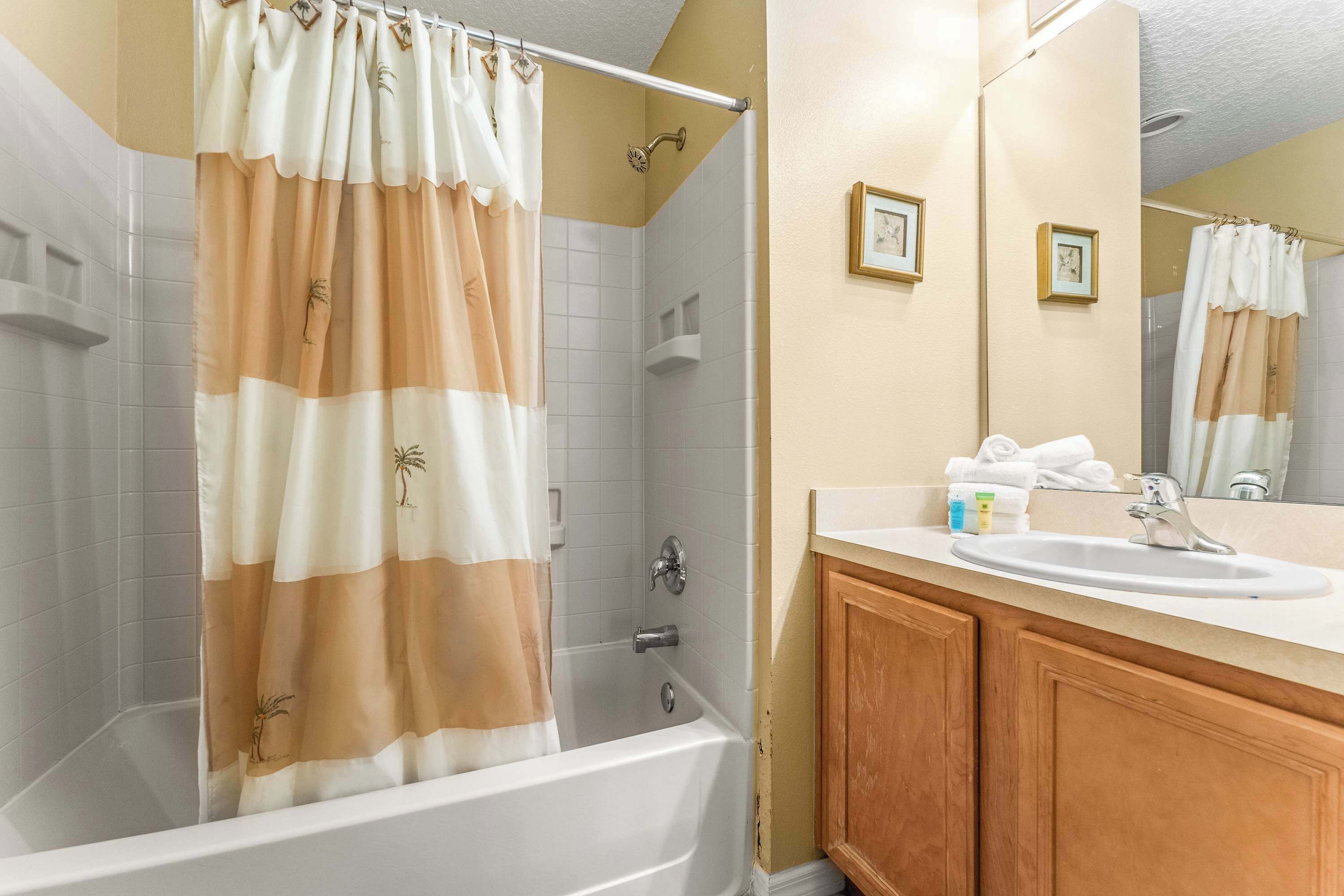 Une salle de bain avec une baignoire, une douche, un meuble-lavabo et des armoires en bois.