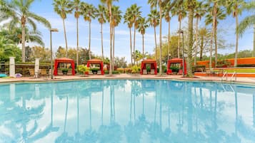Una piscina al aire libre, sombrillas, sillones reclinables de piscina