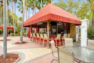 An outdoor patio area with a red-striped roof, several tables and chairs, and a food service counter.