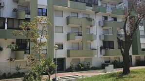 A multi-story residential building with balconies, a paved courtyard, and surrounding greenery. - 7km from the beach and 14km from downtown Lisbon. Cozy, family-friendly apartment! (Almada)