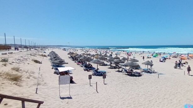 A beach with rows of sun loungers and umbrellas, a clear sky, and the ocean in the background. - 7km from the beach and 14km from downtown Lisbon. Cozy, family-friendly apartment! (Almada)