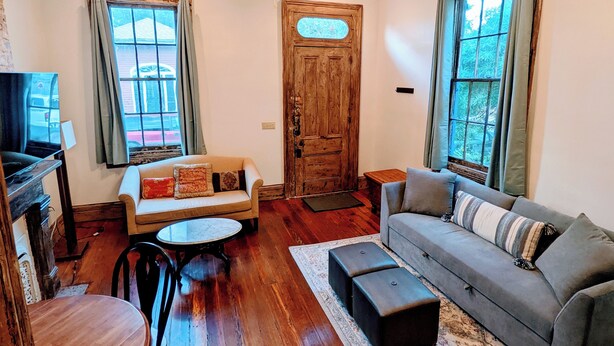 A cozy living room with a wooden floor, a ceiling fan, a sofa, a coffee table, and a TV.