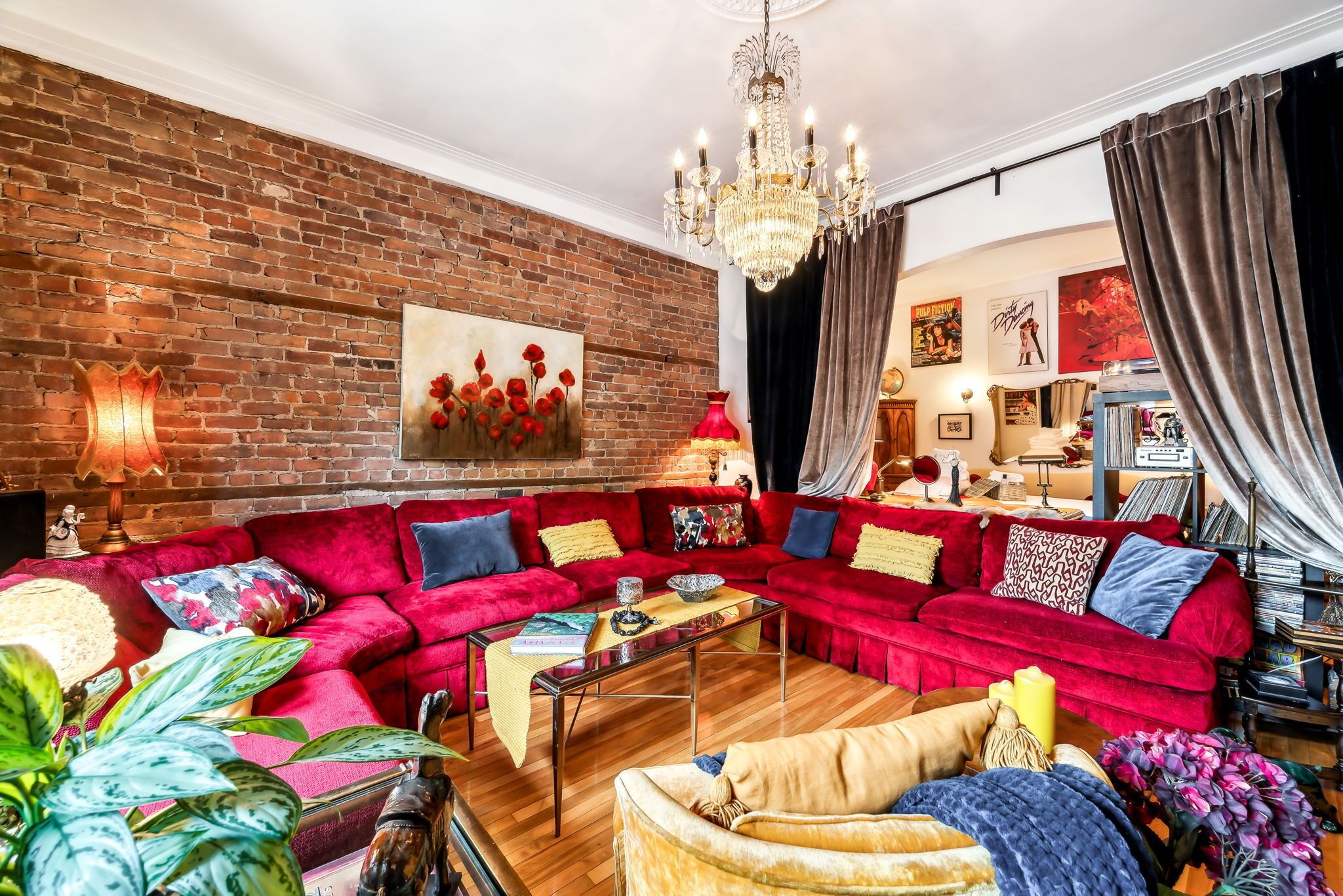 Uma sala de estar aconchegante com um sofá seccional vermelho, um candelabro e uma parede de tijolos.