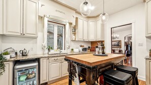 A kitchen with white cabinetry, a wooden island, and a refrigerator.