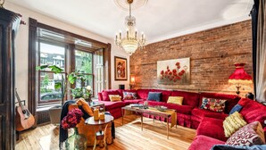 A cozy living room with a red sofa, a wooden coffee table, and a chandelier.