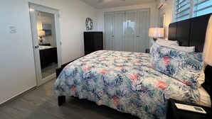 A bedroom with a bed, a ceiling fan, a wardrobe, and a window with blinds.