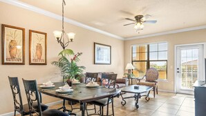 A dining area with a table set for four, surrounded by chairs, a ceiling fan, and a potted plant. - Tuscan Paradise At Bella Piazza (Davenport)