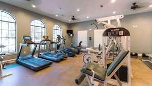 A gym with treadmills, elliptical machines, and weightlifting equipment. - Tuscan Paradise At Bella Piazza (Davenport)