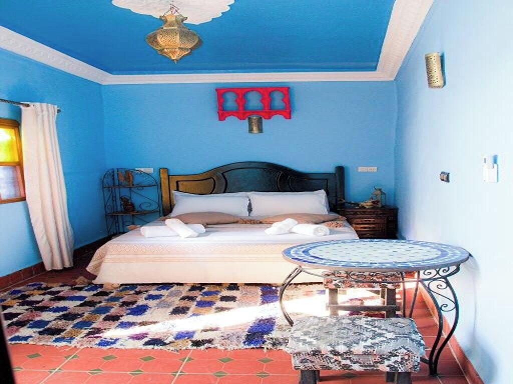 Une chambre à coucher avec un lit, une petite table ronde et un tapis à motifs.