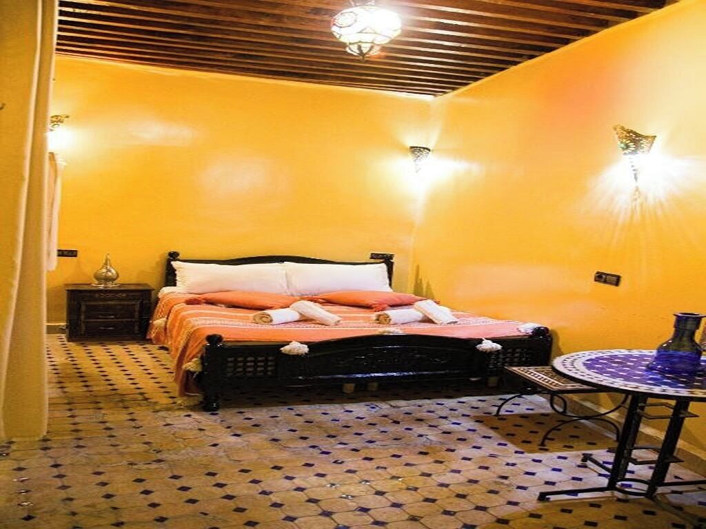 Een kamer met een bed, een klein tafeltje en een vloer met patroon.