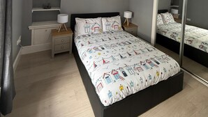 A bedroom with a bed, bedside tables, a mirror, and a painting on the wall.