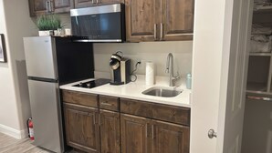 A compact kitchen with a refrigerator, microwave, stove, sink, and wooden cabinets.