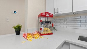 A kitchen with white cabinets, a popcorn machine, and a plant.