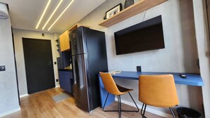 A compact kitchen with a black refrigerator, a blue countertop, and two chairs.