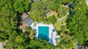 An aerial view of a property with a swimming pool surrounded by trees, a tennis court, and a small building. - Brigantine Quarters 3BR/3.5BA in Shipyard, Private Beach Gate, 2 Pools and MORE (Hilton Head Island)