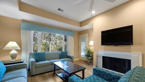 A living room with a sofa, armchairs, a coffee table, a fireplace, and a TV. - Brigantine Quarters 3BR/3.5BA in Shipyard, Private Beach Gate, 2 Pools and MORE (Hilton Head Island)