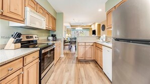 A kitchen with wooden cabinets, a stainless steel refrigerator, a microwave, and a dishwasher. - Brigantine Quarters 3BR/3.5BA in Shipyard, Private Beach Gate, 2 Pools and MORE (Hilton Head Island)