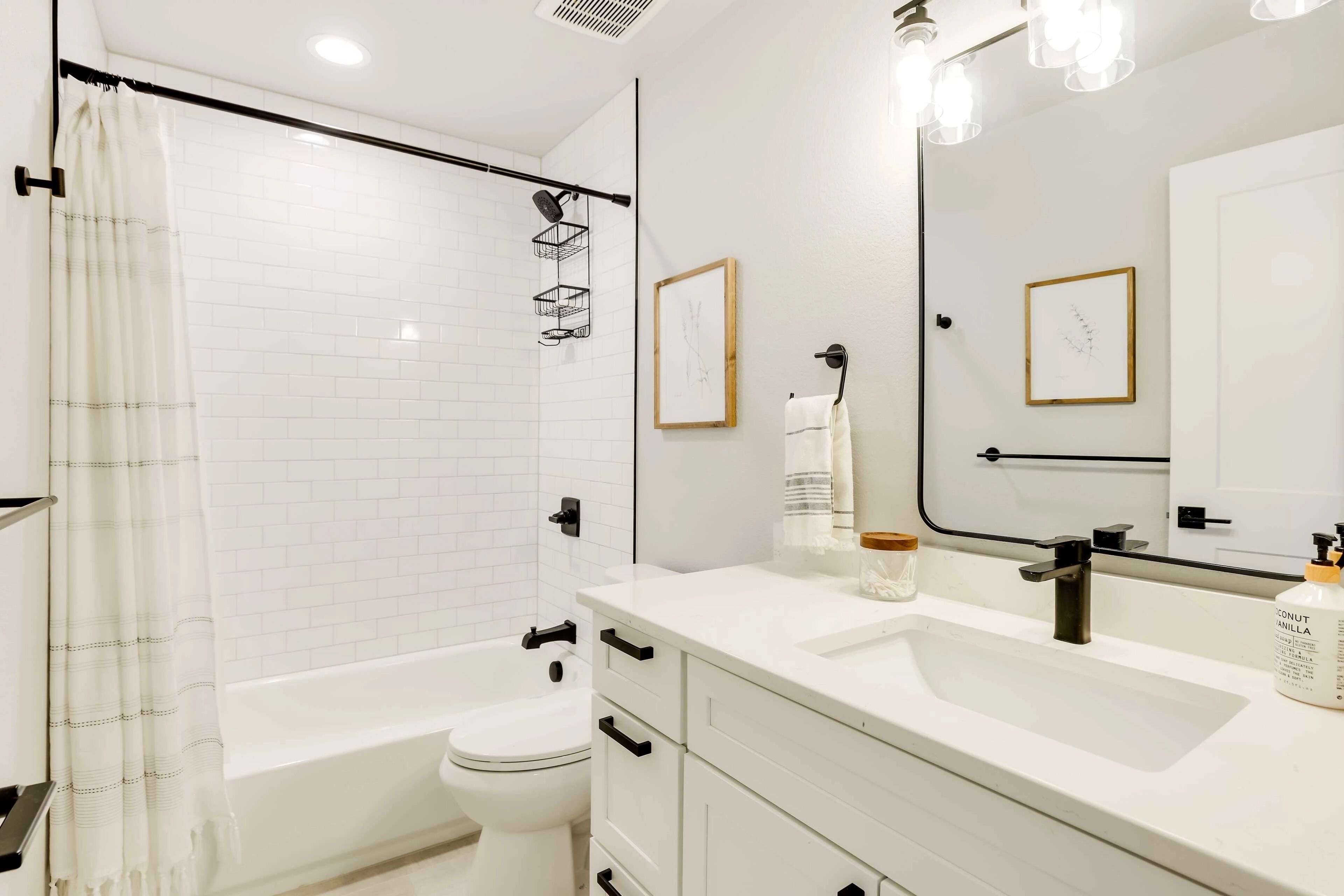 A modern bathroom with a bathtub, toilet, and a vanity with a mirror.