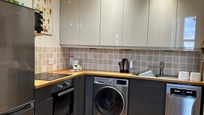 A compact kitchen with stainless steel appliances, a washing machine, and a dishwasher. - Stunning 1-bed Flat W/seaview, Garden Pet Friendly (Herne Bay)