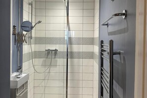 A modern bathroom with a glass shower enclosure, a sink, and a towel rack.