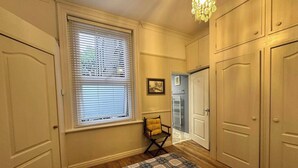 A bedroom with a bed, a chair, a window with blinds, a chandelier, and a door. - Stunning 1-bed Flat W/seaview, Garden Pet Friendly (Herne Bay)