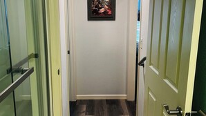 A hallway with a glass door on the left, a wooden door on the right, and a framed picture on the wall. - Adorable 2 Bedroom Unit with Boat Parking (Dauphin Island)