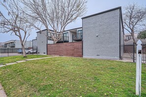 Un edificio moderno con fachada de ladrillo, terraza de madera y patio cercado.