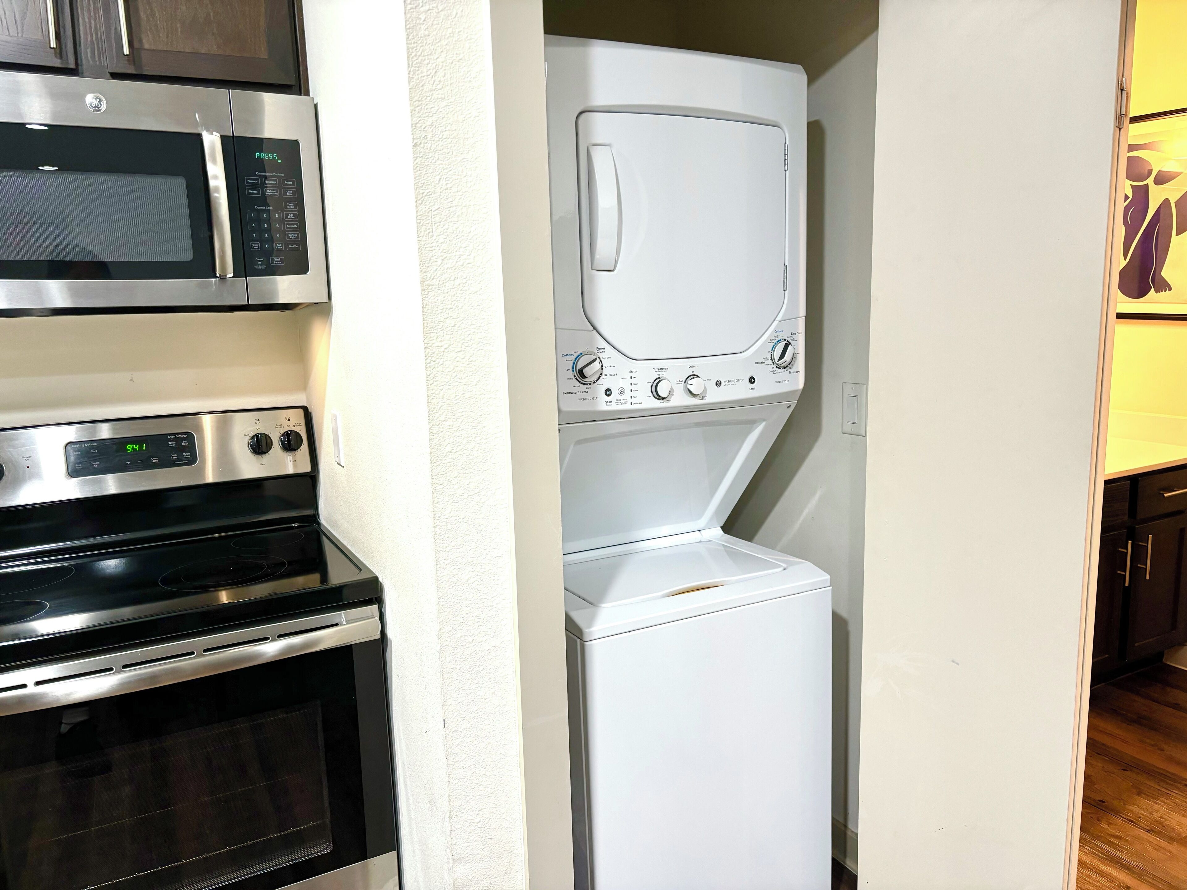 Una cocina compacta con microondas, horno y lavadora-secadora apilada.