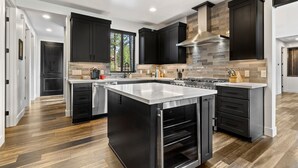 Una cocina moderna con muebles oscuros, una isla central y una campana extractora de acero inoxidable.