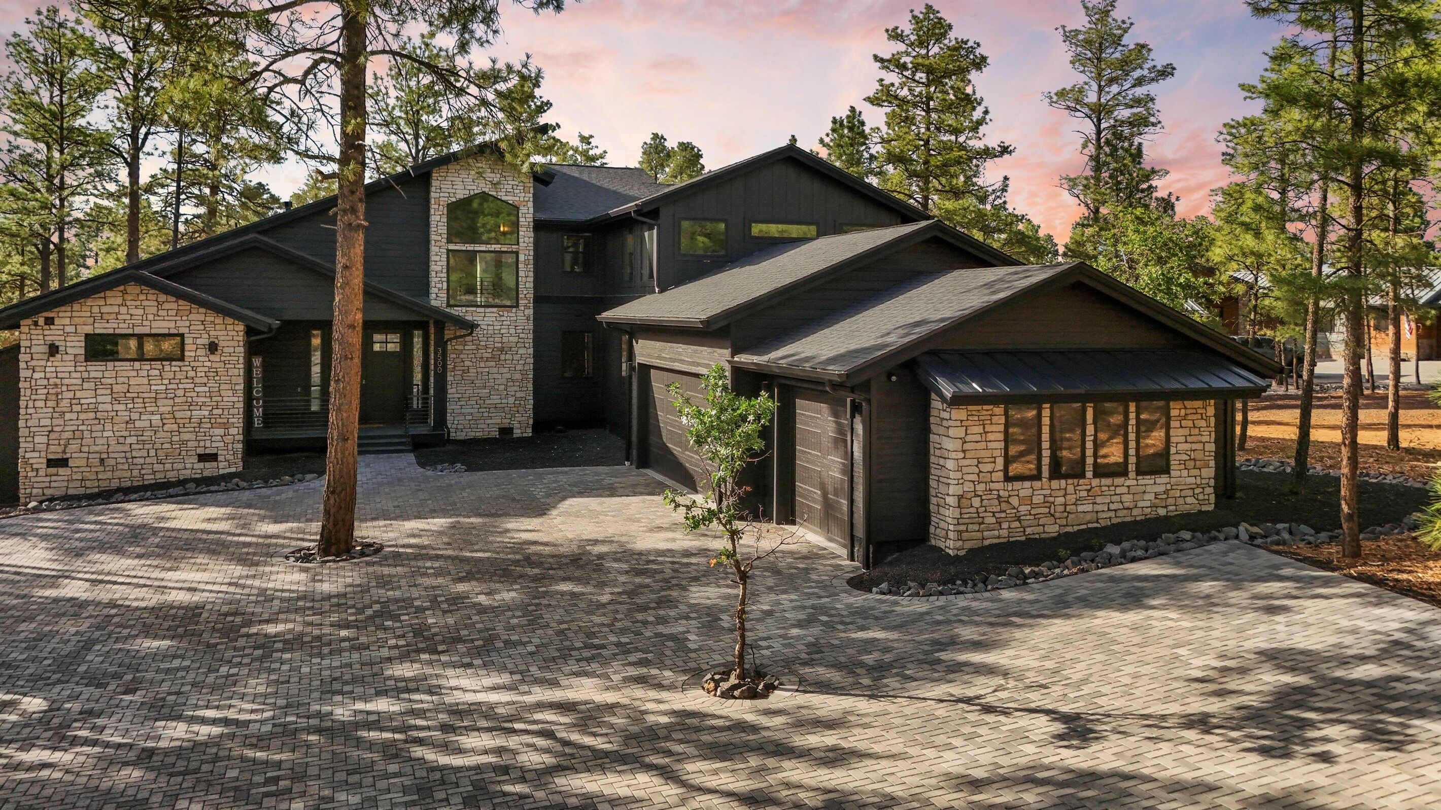 A modern two-story house with a stone facade, a covered porch, and a paved driveway.