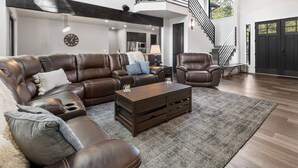 Un salón amplio con un sofá modular grande, una mesa de centro y una escalera que conduce a un nivel superior.