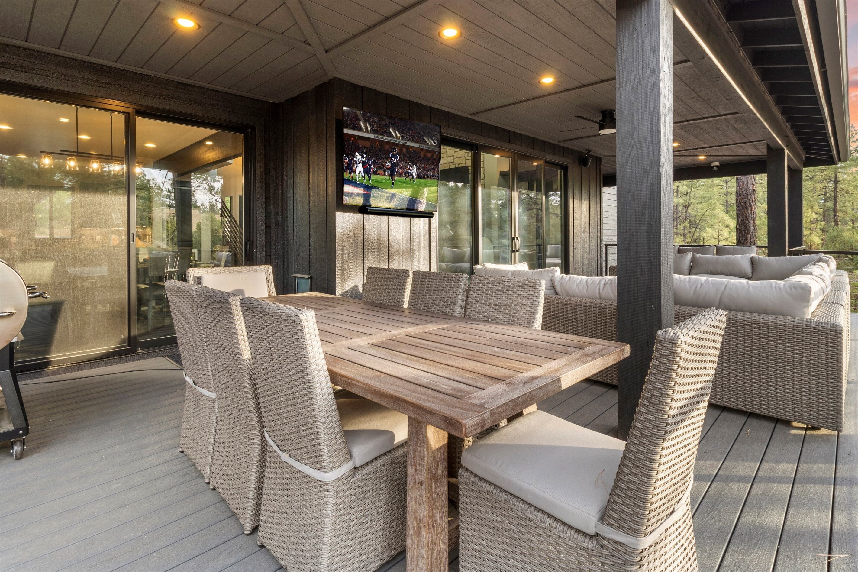 A covered outdoor dining area with a large wooden table and wicker chairs.