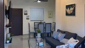 A modern living room with a sofa, coffee table, and a dining area with chairs and a table. - 3Bed-3Bath Villa in Beautiful Punta Cana with AC (Punta Cana)