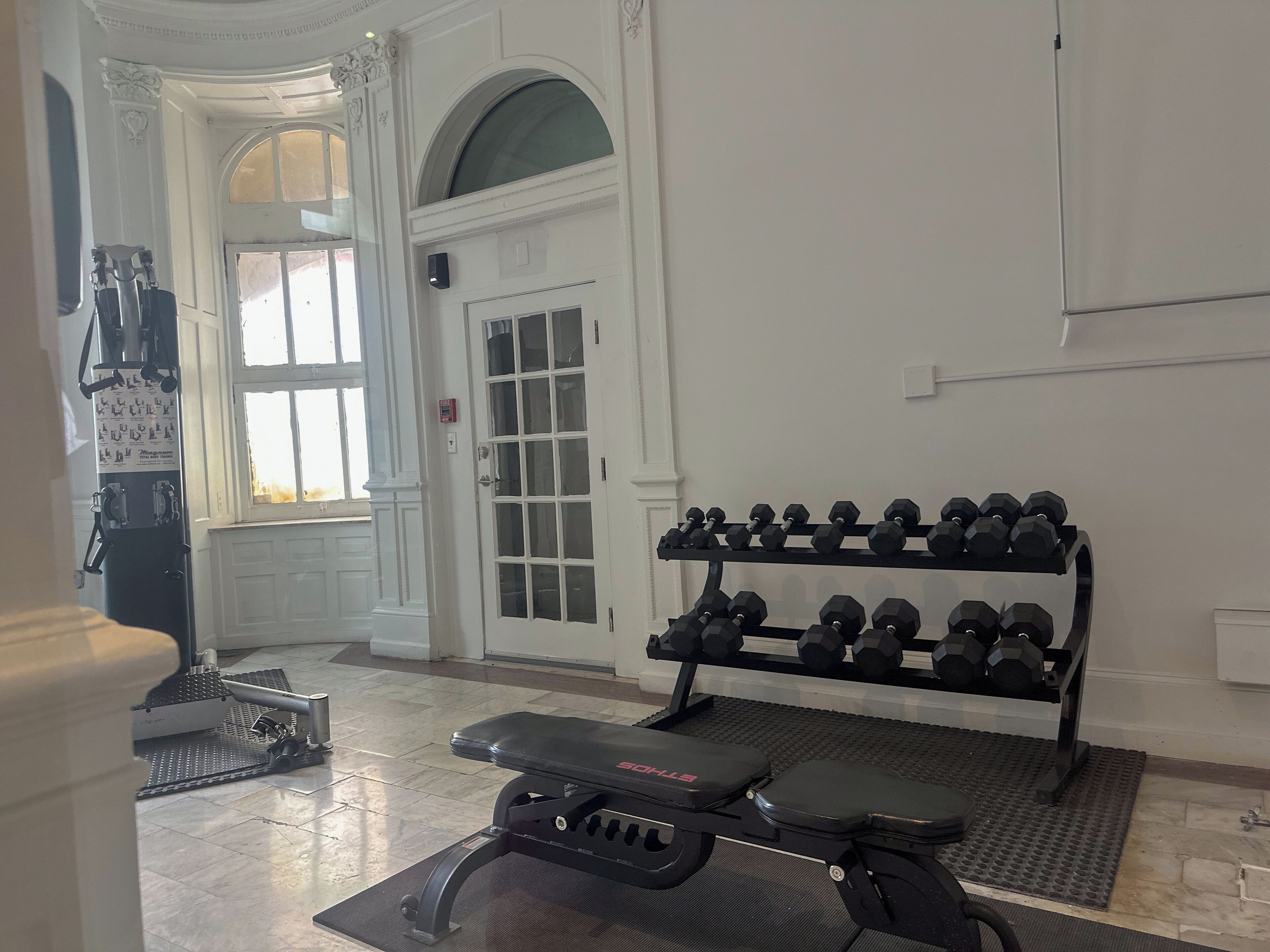 Une salle de sport équipée d’un banc de développé couché, d’un porte-haltères et d’une fenêtre donnant sur l’extérieur.