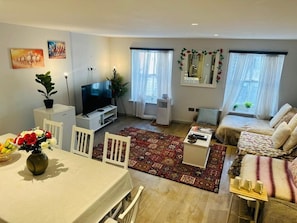 A living room with a TV, sofa, dining table, and chairs.