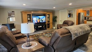 A living room with a flat-screen TV, leather sofas, a coffee table, and a rug. - 4-bedroom cabin in peaceful Lakeside Oregon (Lakeside)