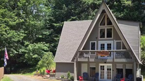 A two-story building with a balcony, a flag, and outdoor seating. - 4-bedroom cabin in peaceful Lakeside Oregon (Lakeside)