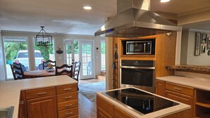 A modern kitchen with wooden cabinets, a built-in oven, microwave, and a large island with an induction cooktop. - 4-bedroom cabin in peaceful Lakeside Oregon (Lakeside)