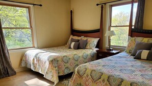 Quarto com duas camas, uma mesa de cabeceira e janela com cortinas.