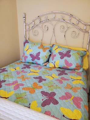 A bed with a floral patterned quilt and two pillows, a white metal headboard, and a plain wall in the background. - 7 rooms and 3 bathrooms NEW! (Weinböhla)