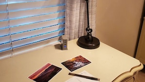 Uma mesa com uma lâmpada, um computador e algumas fotografias.