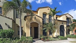 A multi-story building with a beige facade, arched doorways, and a brick-paved entrance area. - SW FL Vacation Paradise! Minimum 1 week stay, long term renters welcome.  (Fort Myers)