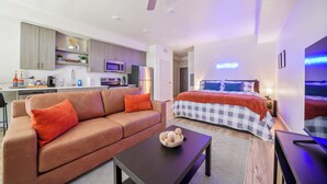 Ein modernes Wohnzimmer mit einer Couch, einem Couchtisch und einem Bett mit kariertem Überwurf.