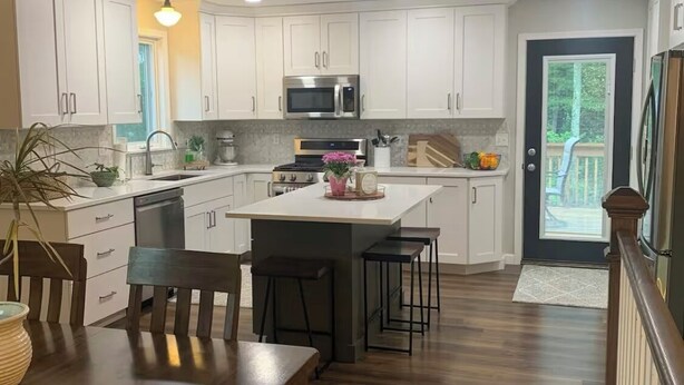 A modern kitchen with white cabinets, stainless steel appliances, and a wooden dining table. - We Are…..2 miles from Beaver Stadium! (State College)